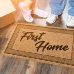 Man and Woman Unpacking Near First Home Welcome Mat, Moving Boxes and Plant.
