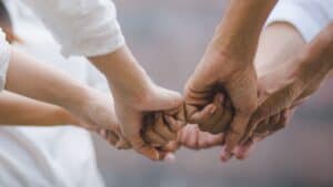 Multiple hands of different individuals joined in a fist bump.