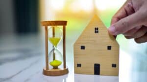 Miniature wooden house and hourglass symbolising property investment.