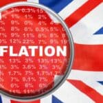 Magnifying glass highlighting inflation rates on UK flag background.