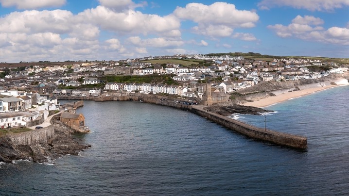 Aerial landscape of the quaint Cornish fishing town of Porthleven in Cornwall with rocky coastline and white sandy beach with harbour wall which is a popular tourist destination