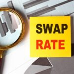 Swap rate concept with financial charts, magnifying glass, and yellow note on desk.