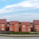 A panoramic landscape row of new build detached homes on a construction site for the UK Government's Right To Buy scheme during a new house shortage with sold sign
