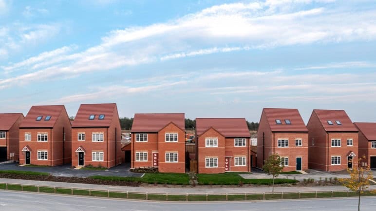 A panoramic landscape row of new build detached homes on a construction site for the UK Government's Right To Buy scheme during a new house shortage with sold sign