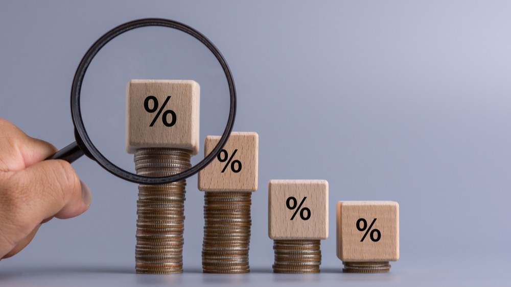 Male hand holding magnifier glass to wooden cube with question mark icon on stacked coin, Business growth analysis, increasing profits, business growth.