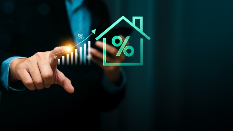 Businessman pointing at rising bar chart with glowing percentage symbol and house icon, representing increasing mortgage rates, home loan growth, interest rate trends, real estate investment finance