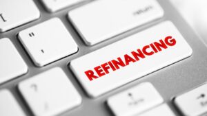 Refinancing is the replacement of an existing debt obligation with another debt obligation under a different term and interest rate, text concept button on keyboard