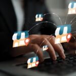 Hands typing on a keyboard with digital store icons and location markers representing online shopping and retail technology concepts Gluon.