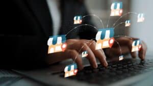 Hands typing on a keyboard with digital store icons and location markers representing online shopping and retail technology concepts Gluon.