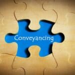 Blue puzzle piece with 'Conveyancing' text on wooden background.
