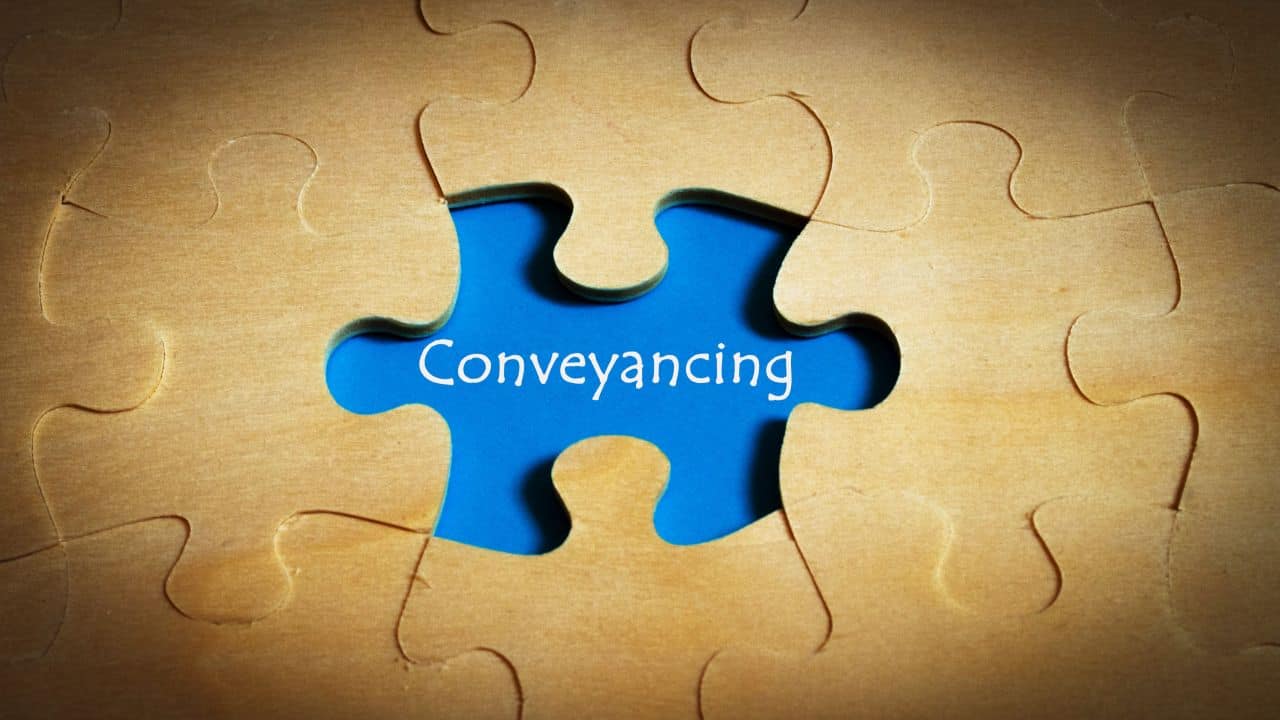 Blue puzzle piece with 'Conveyancing' text on wooden background.